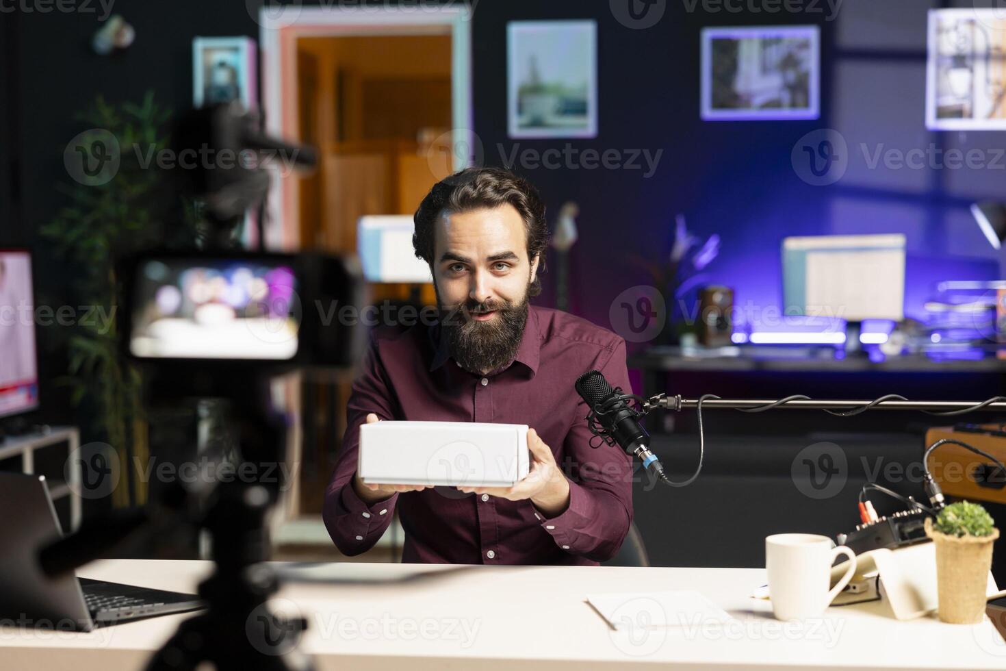 Tech guru filming packaged product unboxing for technology vlog using professional camera. Influencer urging fans to buy sponsoring partner merchandise, recording with high quality gear photo