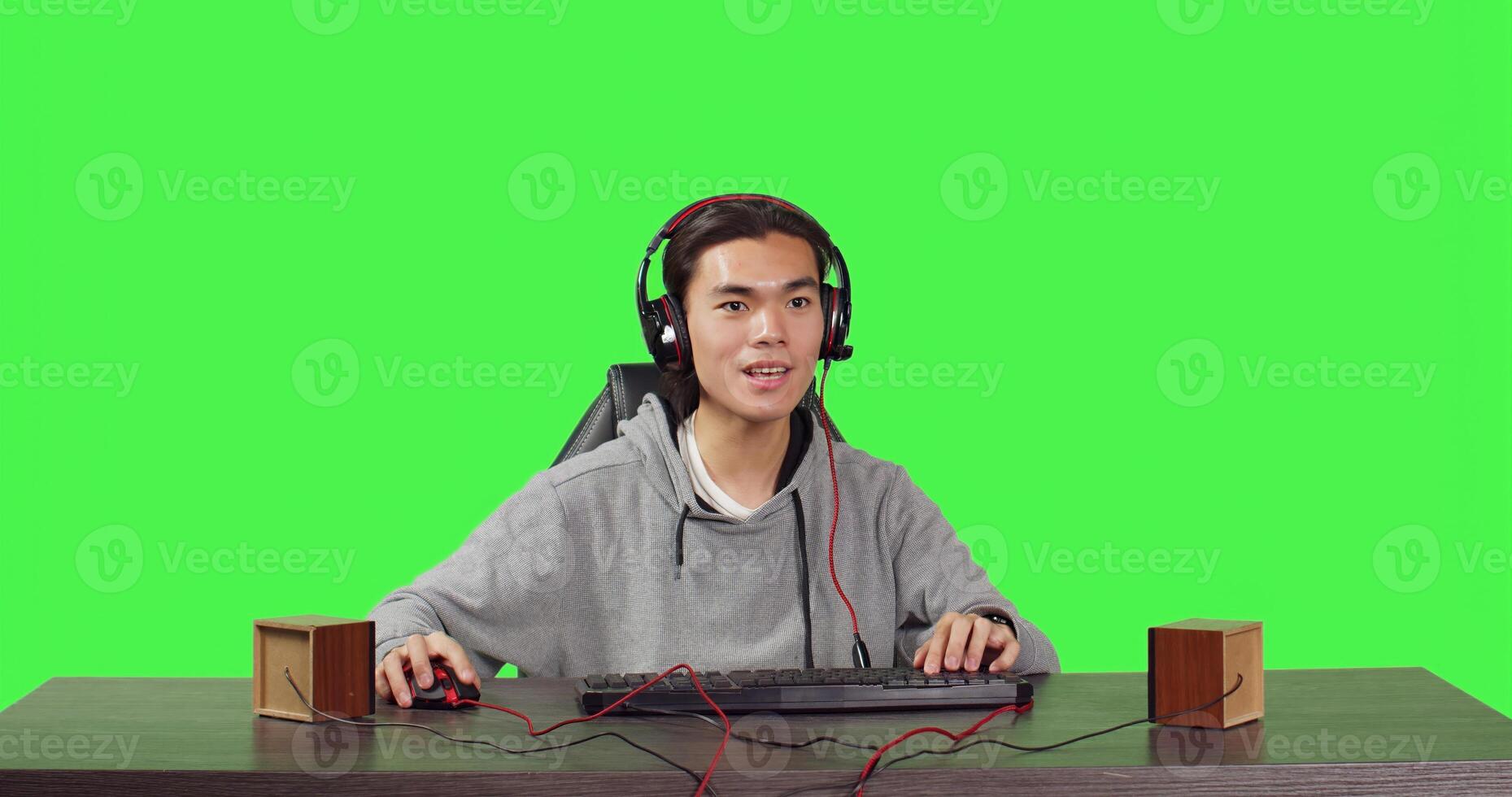 POV of player competing at games on computer while speaking on headphones to his friends, playing interactive combat challenge at desk. Asian gamer having fun with his free time. photo