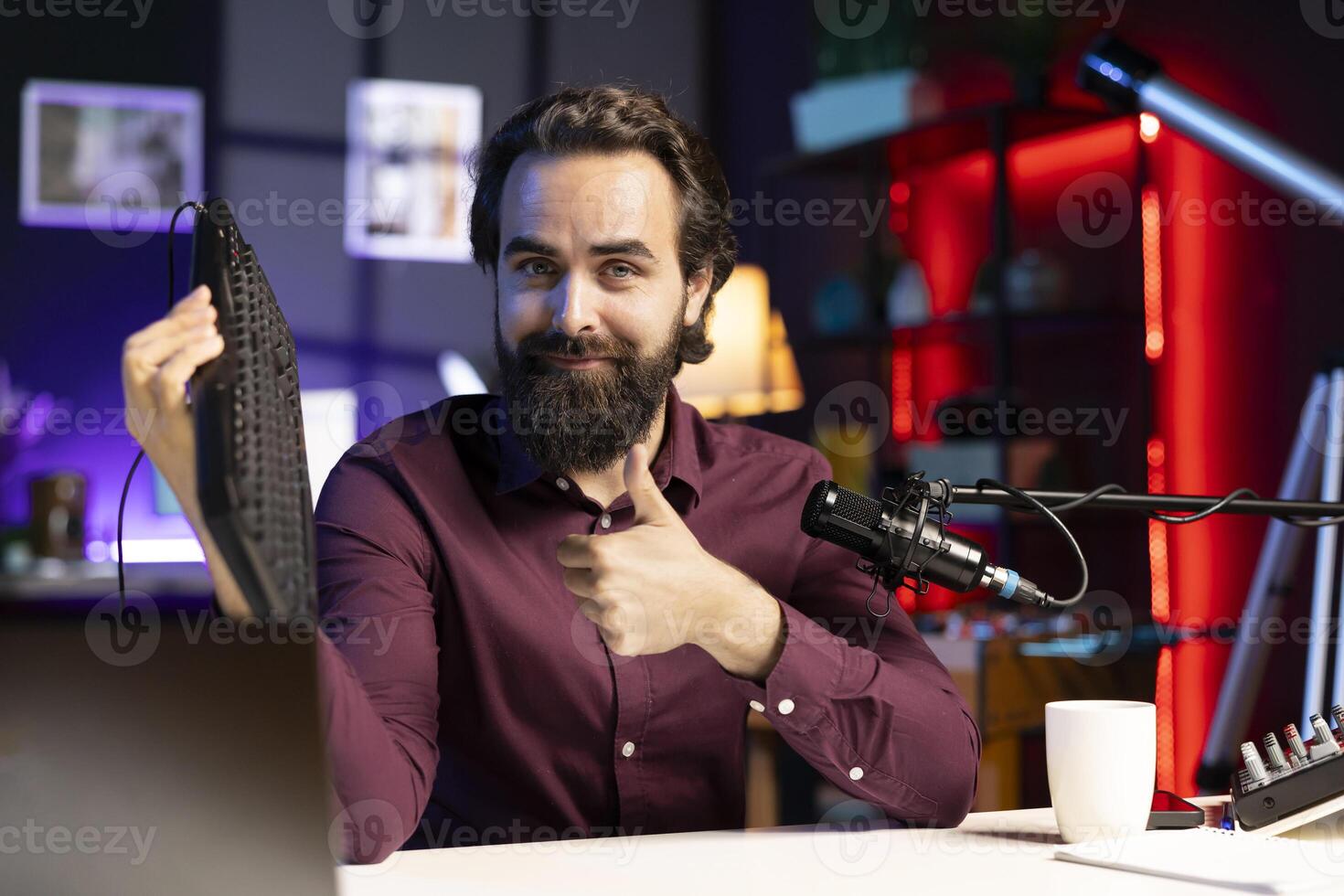 Influencer in studio reviewing gaming keyboard received from sponsoring brand. Online show host paid to promote bluetooth wireless computer peripheral to viewers during live broadcast photo