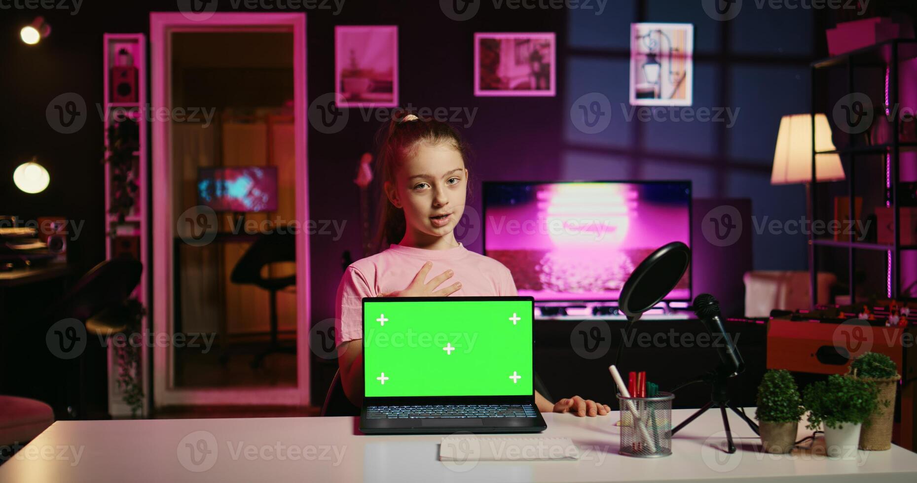 Young girl tech content creator filming technology review of green screen laptop, unboxing it and presenting specifications to audience. Cute gen Z influencer showing mockup notebook device to viewers photo