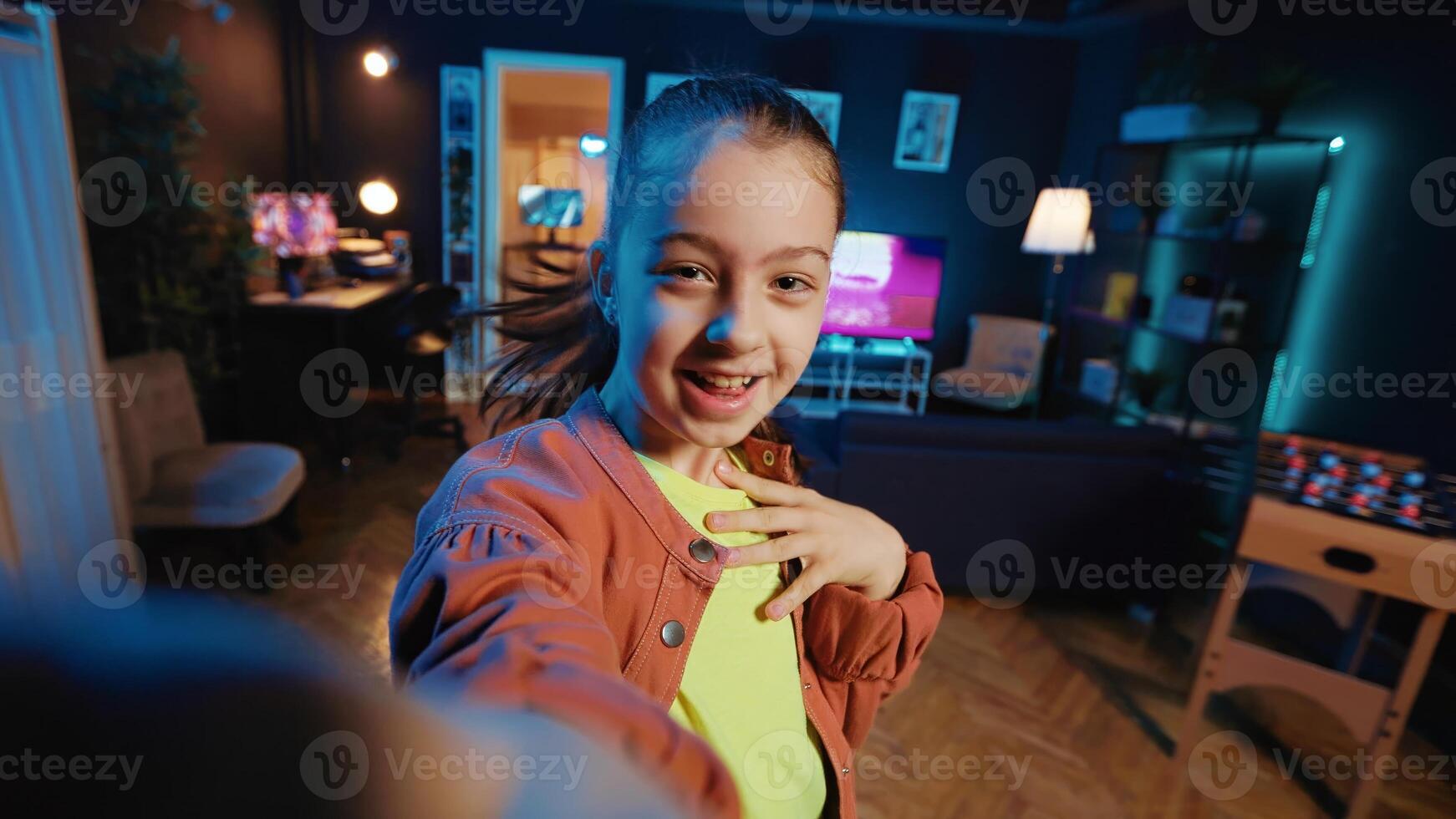 Small girl taking part in viral dance craze after seeing favorite celebrities doing it, filming POV style . Little kid doing trendy dancing challenge, recording with selfie smartphone camera photo