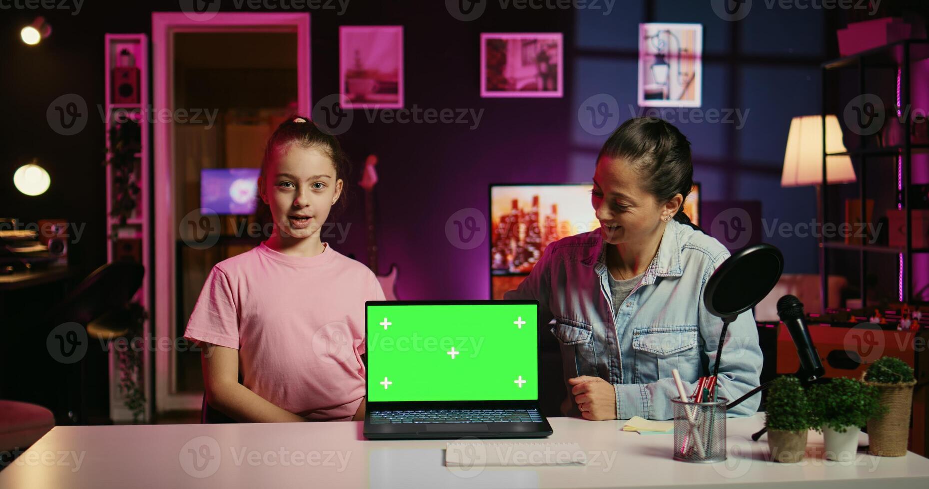 Happy child in apartment studio presenting advertisement from sponsoring brand on isolated screen laptop. Gen Z girl using mockup notebook to present promotion from media partner to followers photo