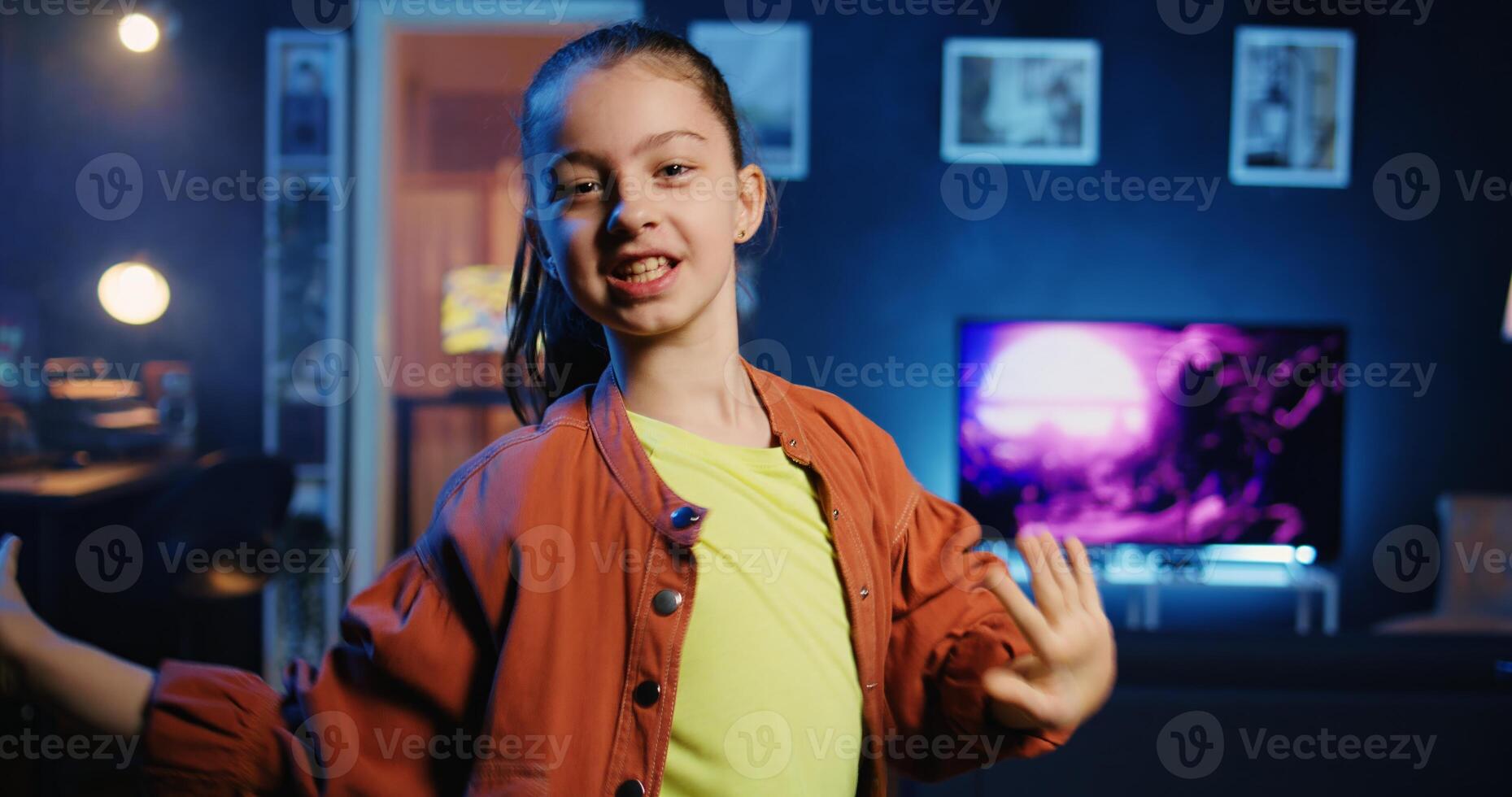 Talented gen z influencer doing viral dance choreography, creating content to generate views and engagement. Happy child having fun dancing around neon lit living room, entertaining audiences photo