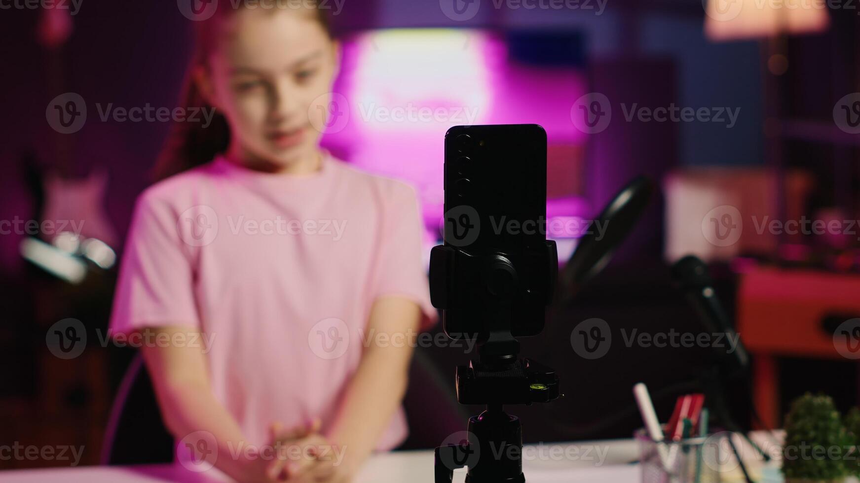 Close up shot of recording gear used by Gen z kid to film for online channel, talking with viewers. Focus on smartphone used by Kid in blurry background discussing topics with young audience photo