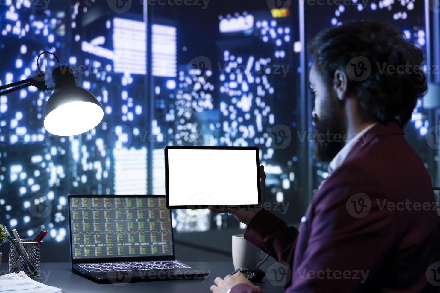 Legal consultant examining blank copyspace display at night, working on obtaining financial success. Company CEO following stock trends to increase funds, using tablet with white screen. photo