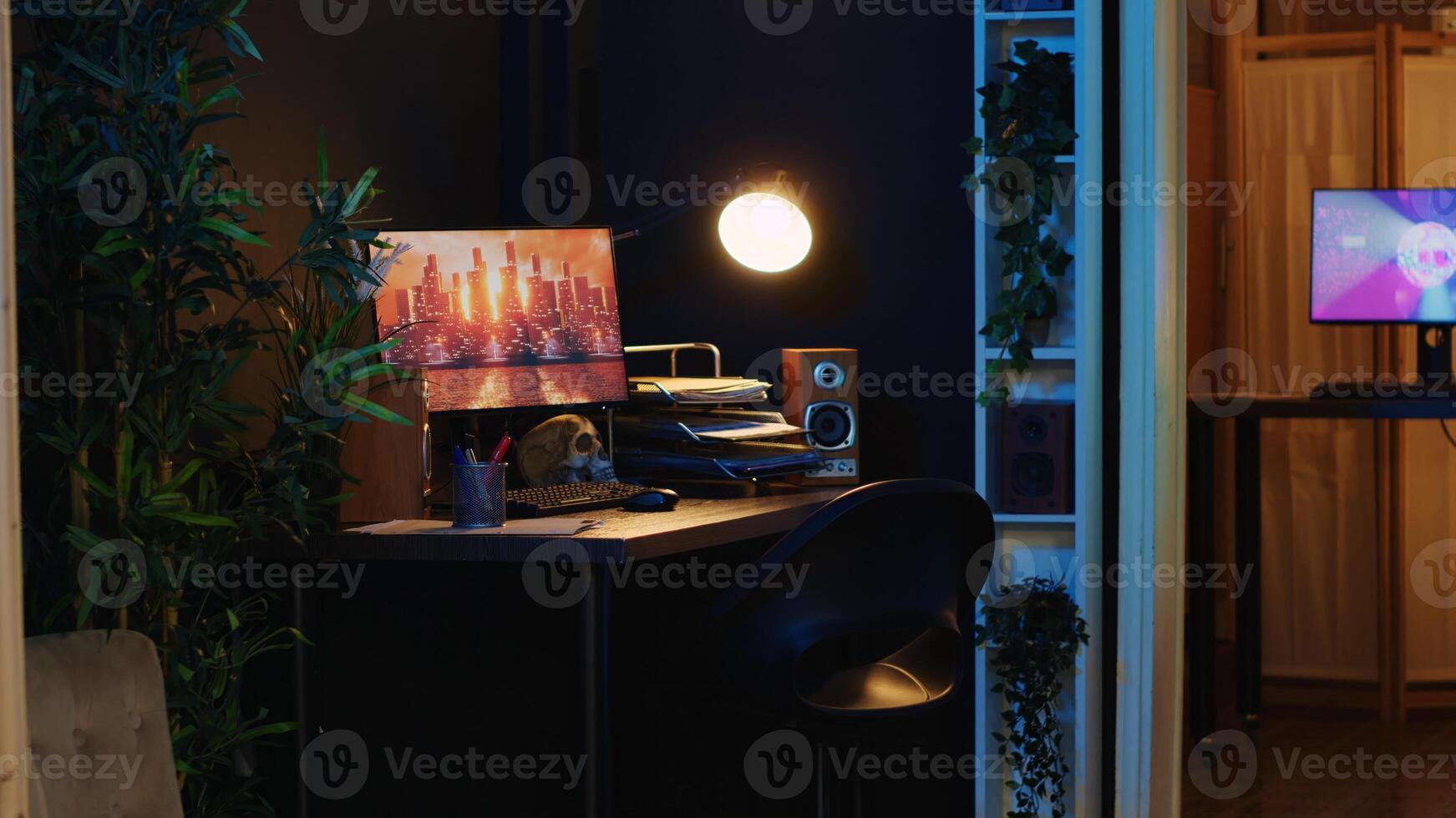 Work desk with computer and house plants in empty house interior with warm lighting. Living room illuminated by neon lights with 3D rendered animations running on powerful PC monitors photo