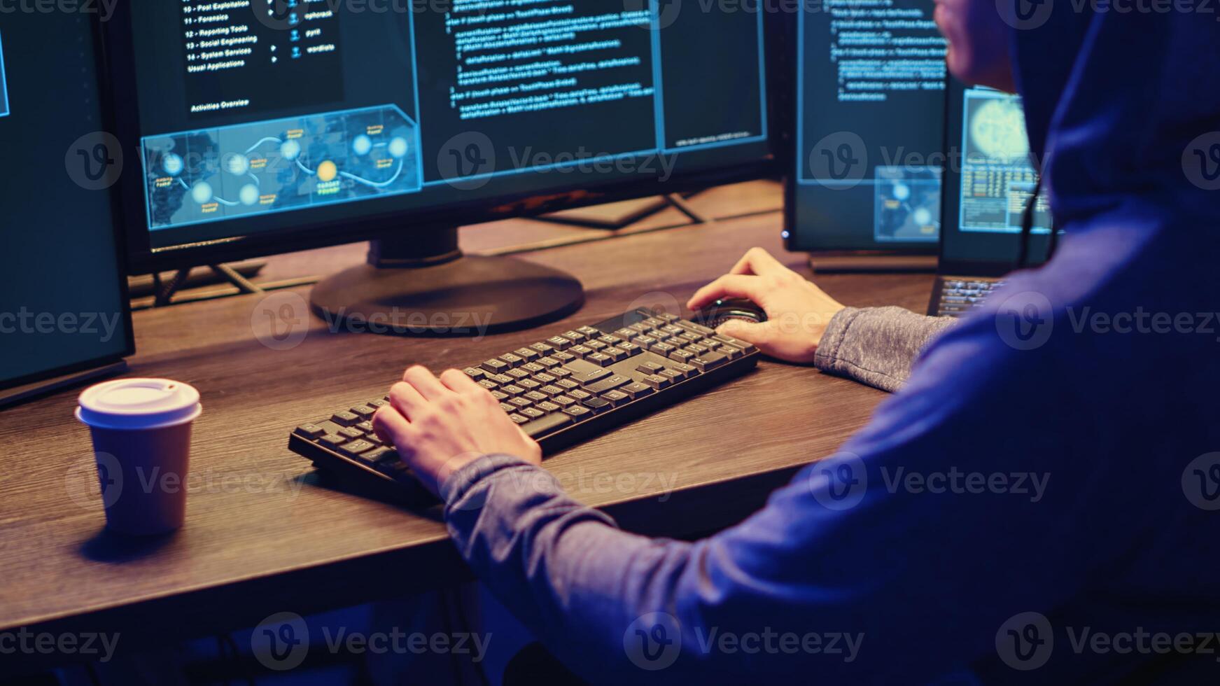 Young hacker drinking coffee while running spyware software designed to gather information from users computers without their knowledge. Script kiddie doing illegal stuff in graffiti painted hideout photo