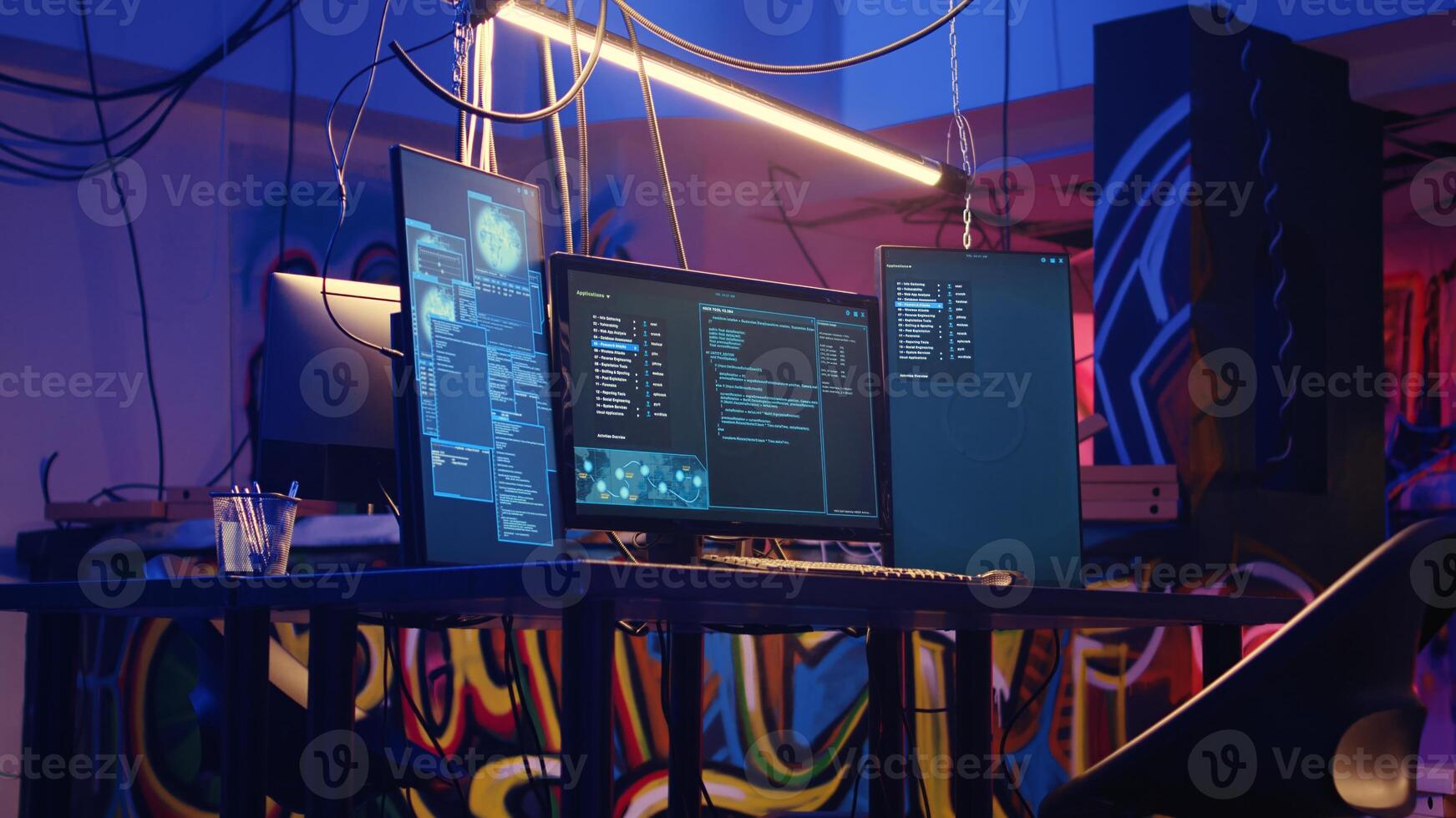 Jib down shot of abandoned basement with graffiti drawings on walls and high tech computer equipment left open running code. Underground hideout used as base of operations by hackers photo
