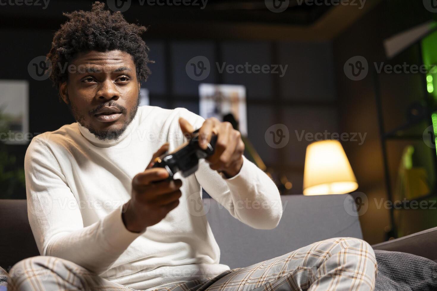 Gamer engaging in online competitive multiplayer tourney using cutting edge gaming console and gamepad. Man in home theatre playing engaging videogame, focused on defeating enemies photo
