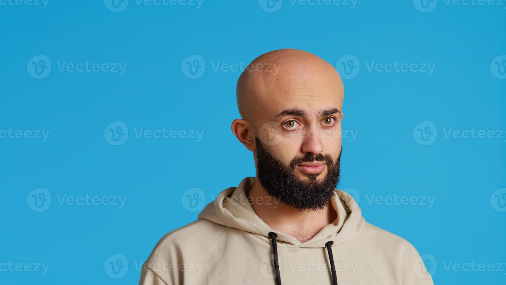 Arab person showing negative sign with fingers, expressing his refusal in front of camera. Middle eastern guy does no symbol in studio, presenting rejection and restriction gesture. Camera 2. photo
