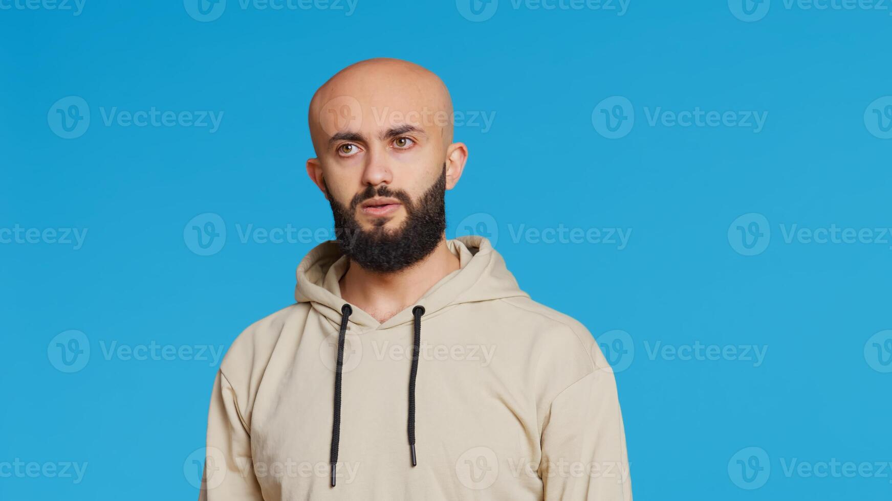 Young guy gesturing no sign over studio background, posing in studio and showing negative emotion. Middle eastern model doing forbidden gesture, expressing his refusal. Camera 2. Handheld shot. photo
