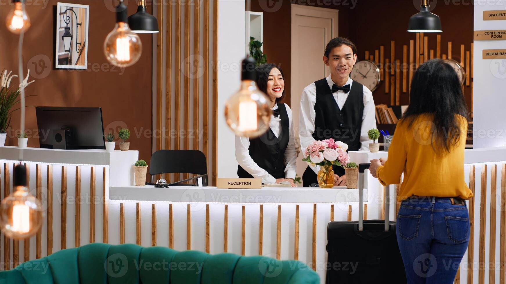 Front desk team greeting guest at five star hotel reception, welcoming person and ensuring easy check in procedure. Woman client entering lobby with luggage, hospitality industry. photo