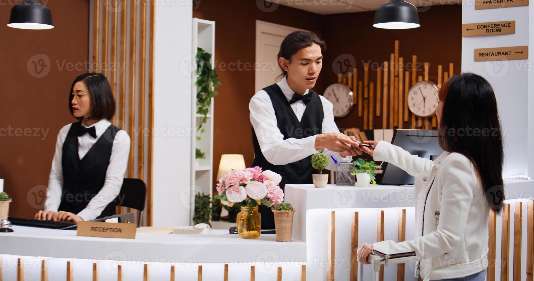 Hotel staff examines passport info for customer identification, finishing check in process at front desk. Receptionist verifying travelling id documents for asian woman arriving at reception. photo