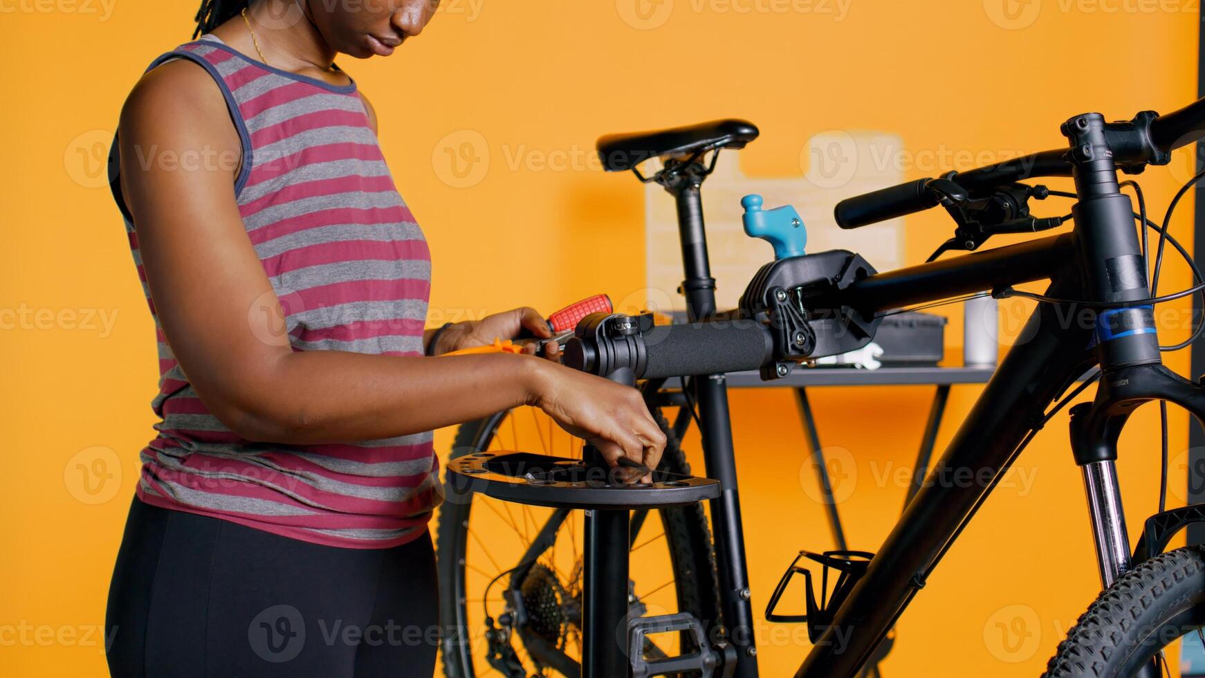 Close up shot of worker preparing work tools before starting refurbishing malfunctioning bicycle, studio background. Expert arranging screwdriver, pliers and hex wrench on equipment support, camera B photo