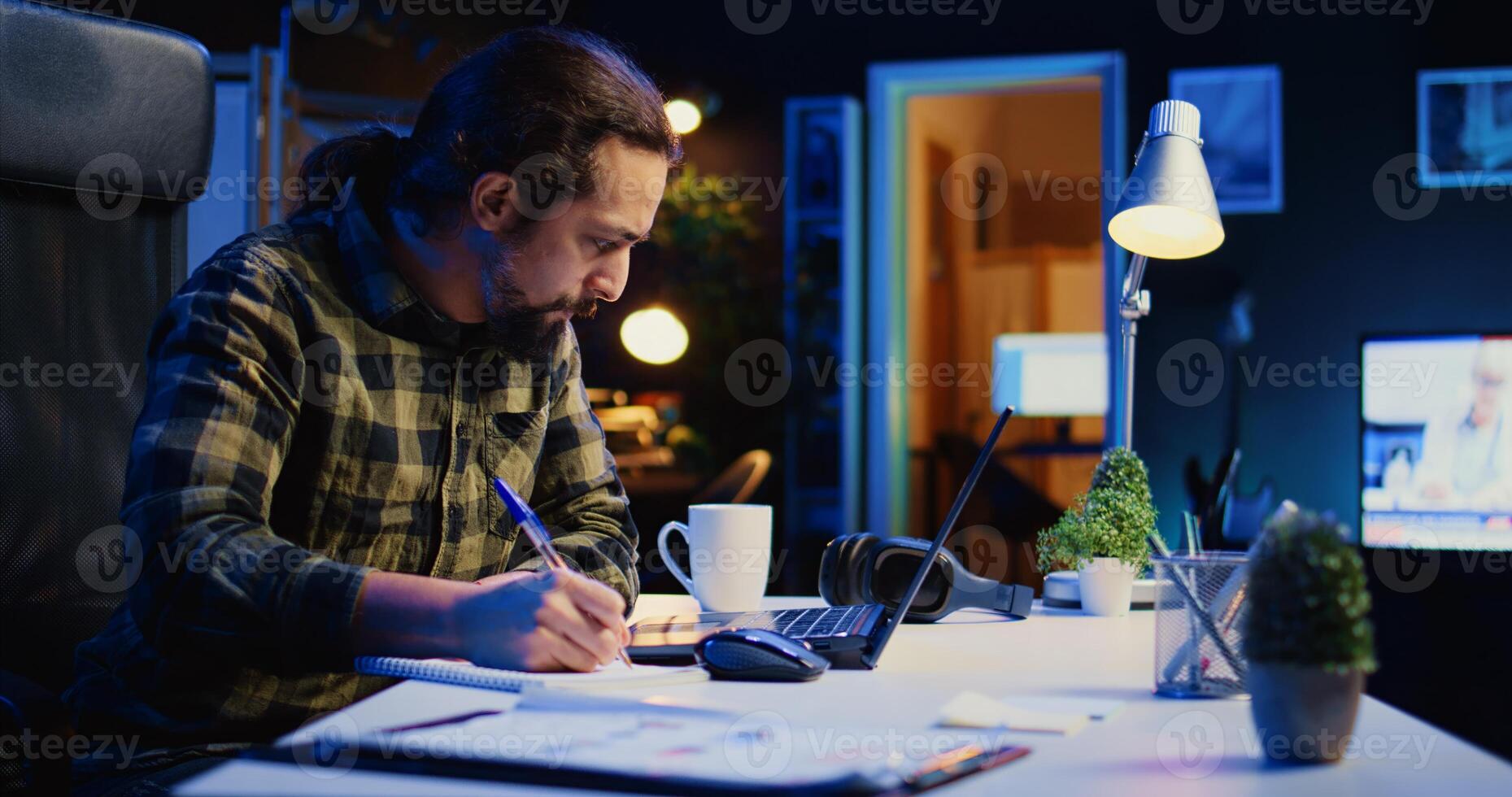Self employed broker investor in home office checking stock exchange profit, calculating using pen and paper. Freelancer in apartment looking at market shares growth, writing on notepad, camera B photo