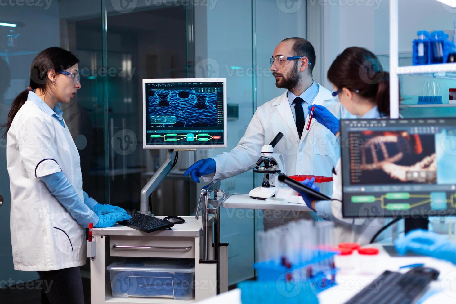 Research scientists working on monitor analyzing virus with chemistry team. Chemists in pharmaceutical lab examining sample for medical experiment with technology for medicine industry. photo