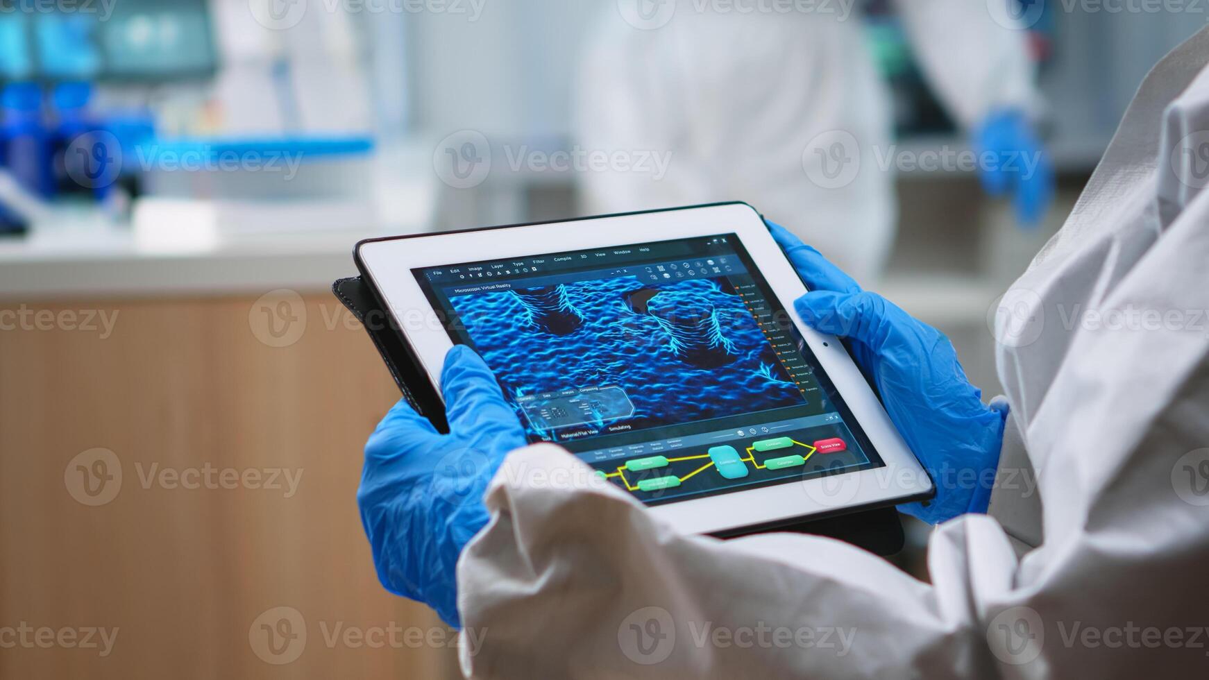 Back view of doctor in protection suit analyzing virus evolution looking on digital tablet. Team of scientists conducting vaccine development using high tech for researching treatment against covid19 photo