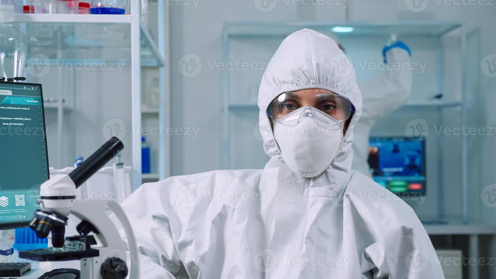 Portrait of overworked biolog looking at camera in modern equipped lab. Team of scientists examining virus evolution using high tech and chemistry tools for scientific research, vaccine development. photo