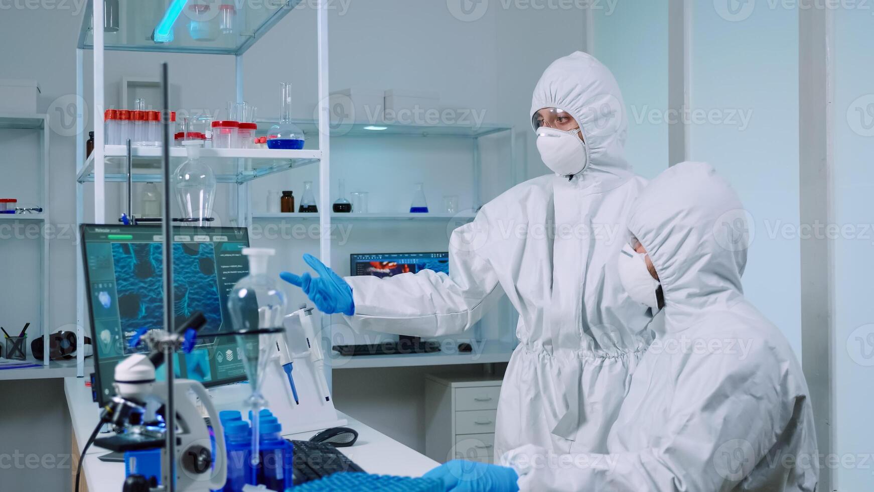 Biotechnology scientist wearing ppe suit researching in equipped laboratory. Team of chemists examining virus evolution using high tech for scientific research of vaccine development against covid19 photo