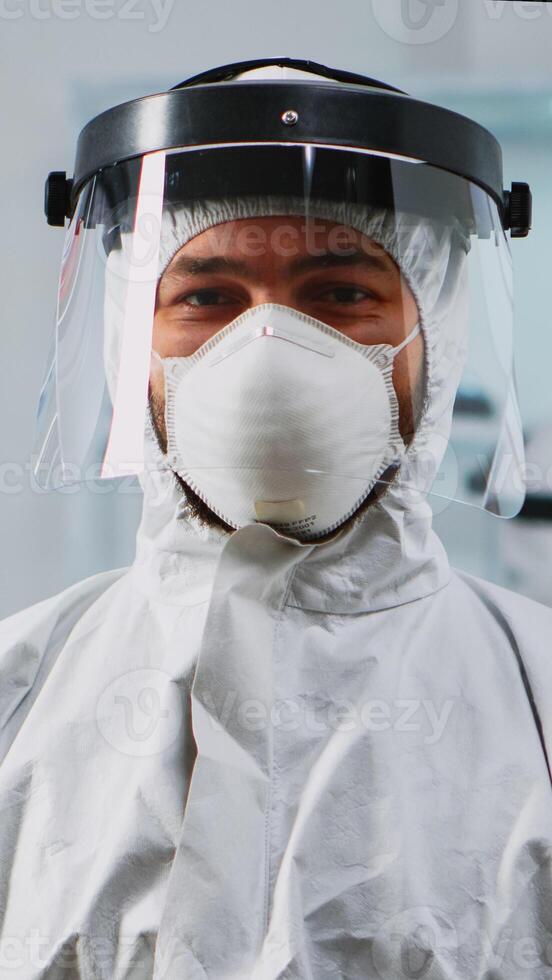 Portrait of scientist man wearing coverall smiling at camera sitting in modern equipped laboratory. Chemist doctor xamining virus evolution using high tech for scientific research, vaccine development photo