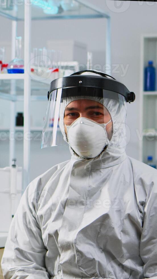 Close up of tired chemist man doctor in coverall working in scientific equipped laboratory. Scientist working with various bacteria, tissue and blood samples, pharmaceutical research for antibiotics photo