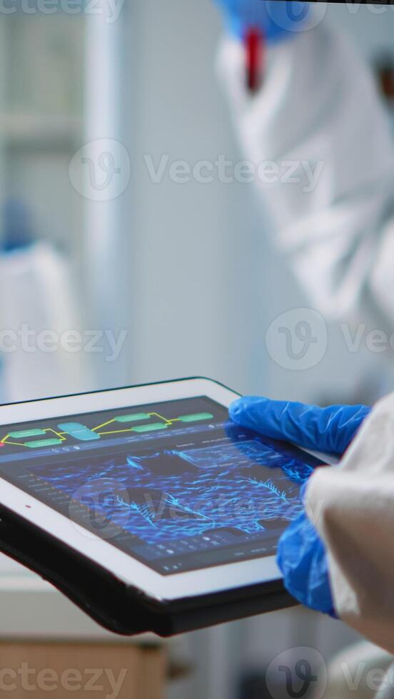Back view of scientist in coverall analyzing virus evolution looking on digital tablet. Team of microbiologists conducting vaccine development using high tech for researching treatment against covid19 photo