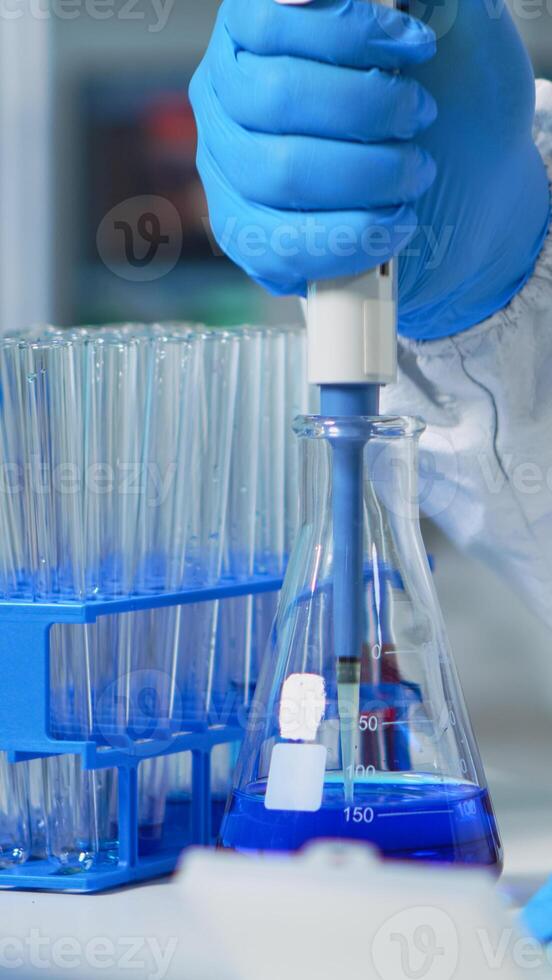 Close up of researcher testing liquid sample using micropipette for new treatment medical laboratory. Team of doctors examining virus evolution using high tech for vaccine development against covid19 photo