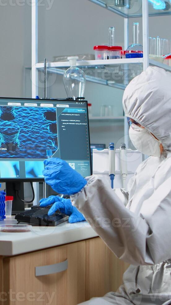Chemist with coverall looking at virus test in equipped lab. Scientist working with various bacteria, tissue and blood samples, concept of pharmaceutical research for antibiotics against covid19 photo