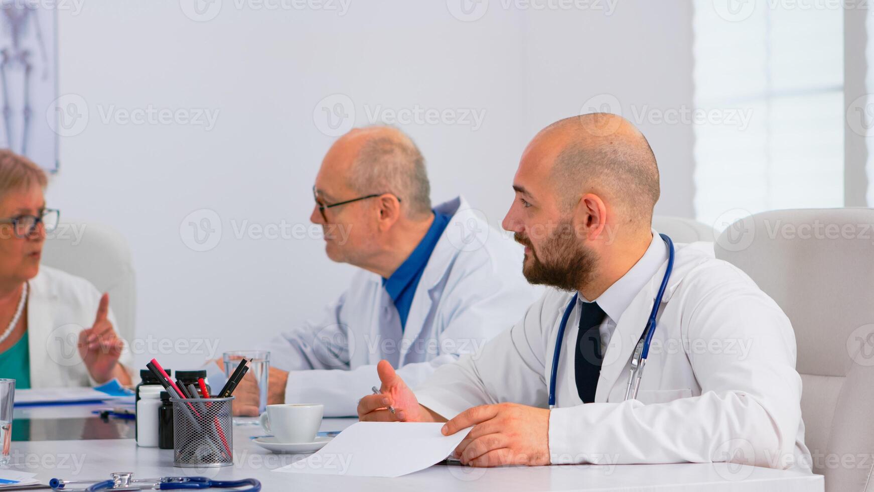Brainstorming teamwork of physicians solving problems of patients in modern hospital meeting room having medical conference. Team of doctors talking about symptoms of disease in clinic office. photo