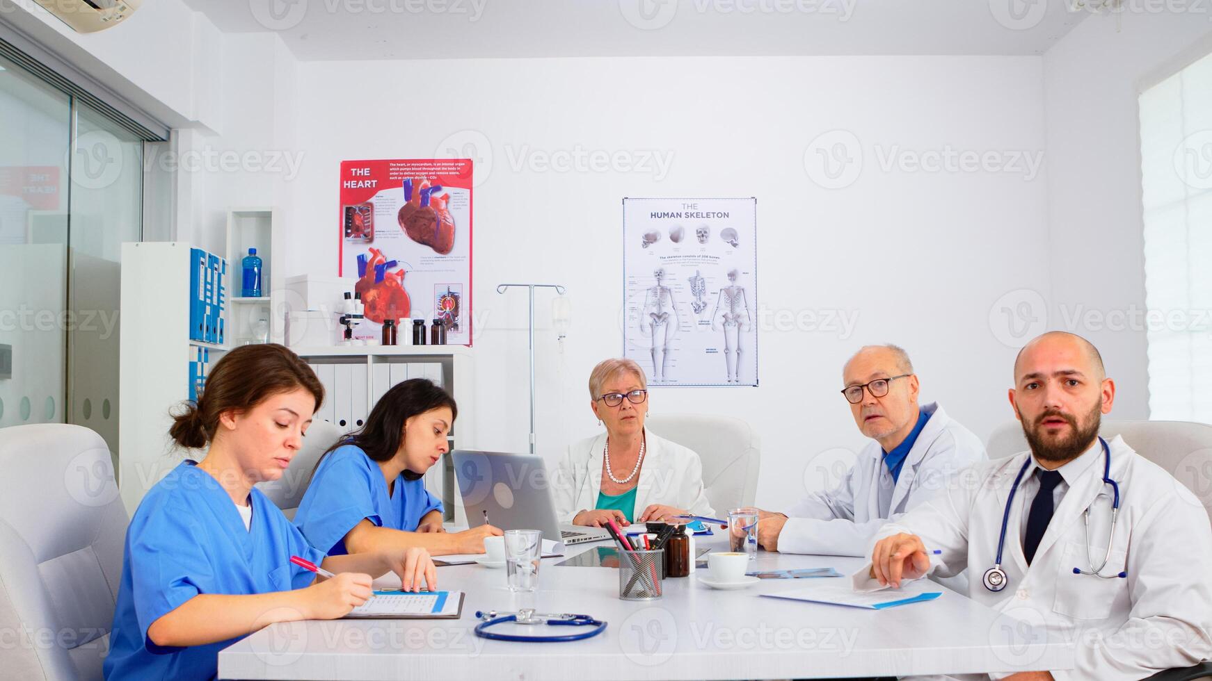 Team of doctors discussing online with chief phisycian, training medical workers group, teaching medic team in virtual conference web camera. Medic having conference sitting in hospital office photo