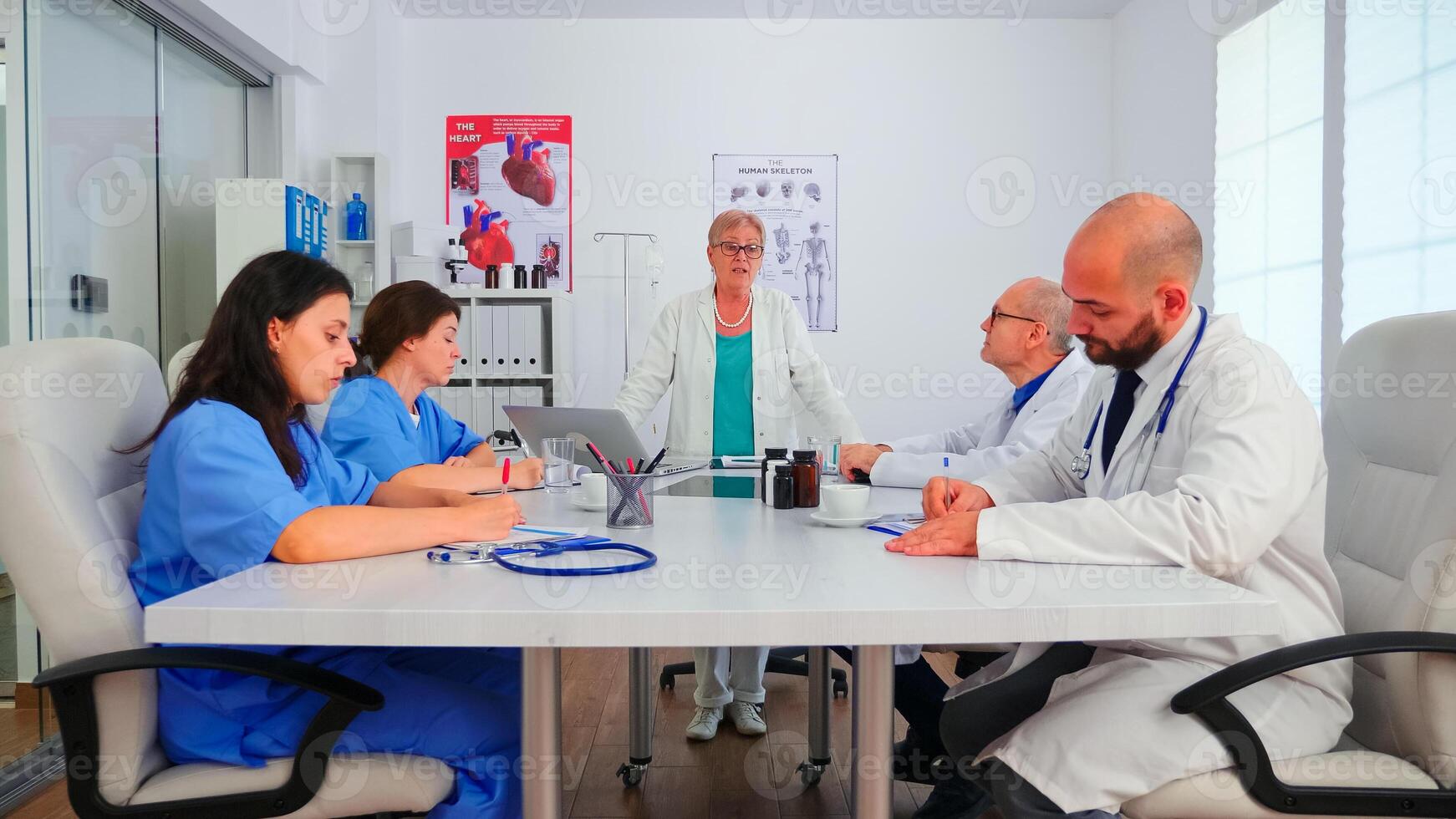 Nurses listening medical specialist during briefing about patient diagnosis and taking notes in hospital conference room. Clinic therapist talking with colleagues about disease, expert specialist photo