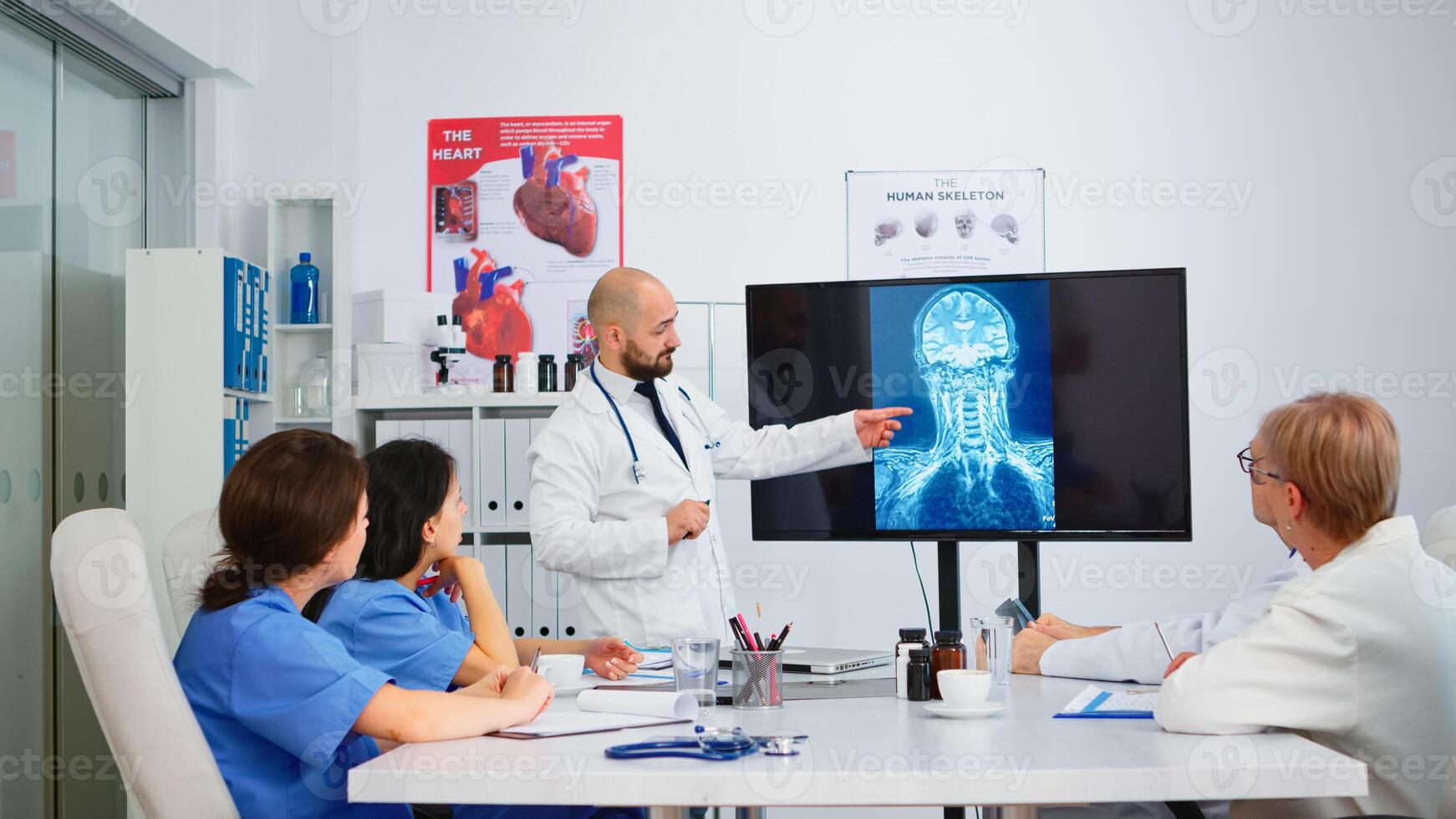 Doctors in white coats sitting in hospital boardroom working with digital x-ray spin image discussing symptoms of disease for further treatment. Practical work of interns, medical examination photo
