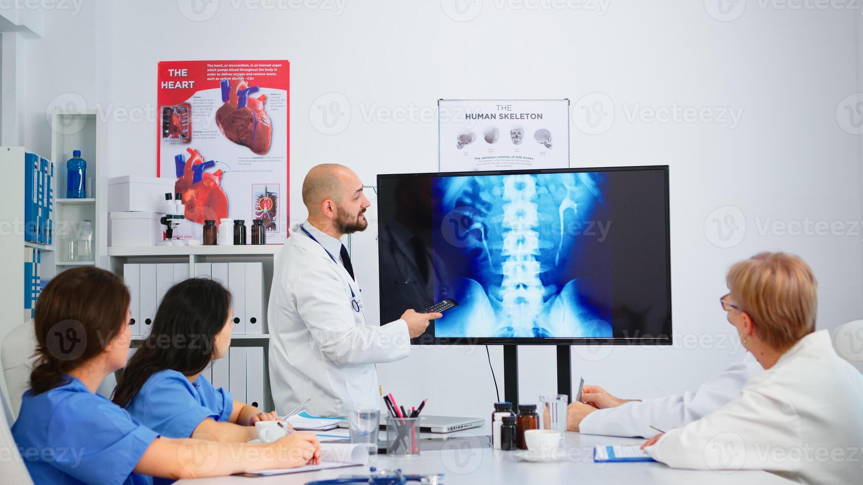 Cvalified head doctor in white coat sitting in hospital boardroom explaining spin functions pointing on digital x-ray image. discussing symptoms of disease for further treatment photo