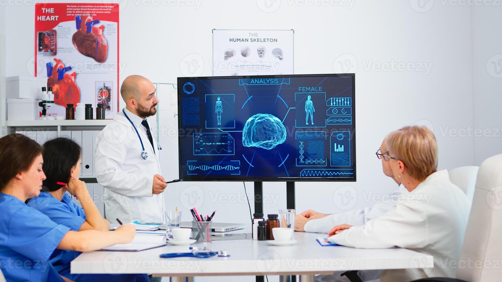 Medical worker presenting report on digital screen about internal human brain in front of colleagues pointing on monitor in hospital office during brainstorming. Team analysing diagnosis of patients photo