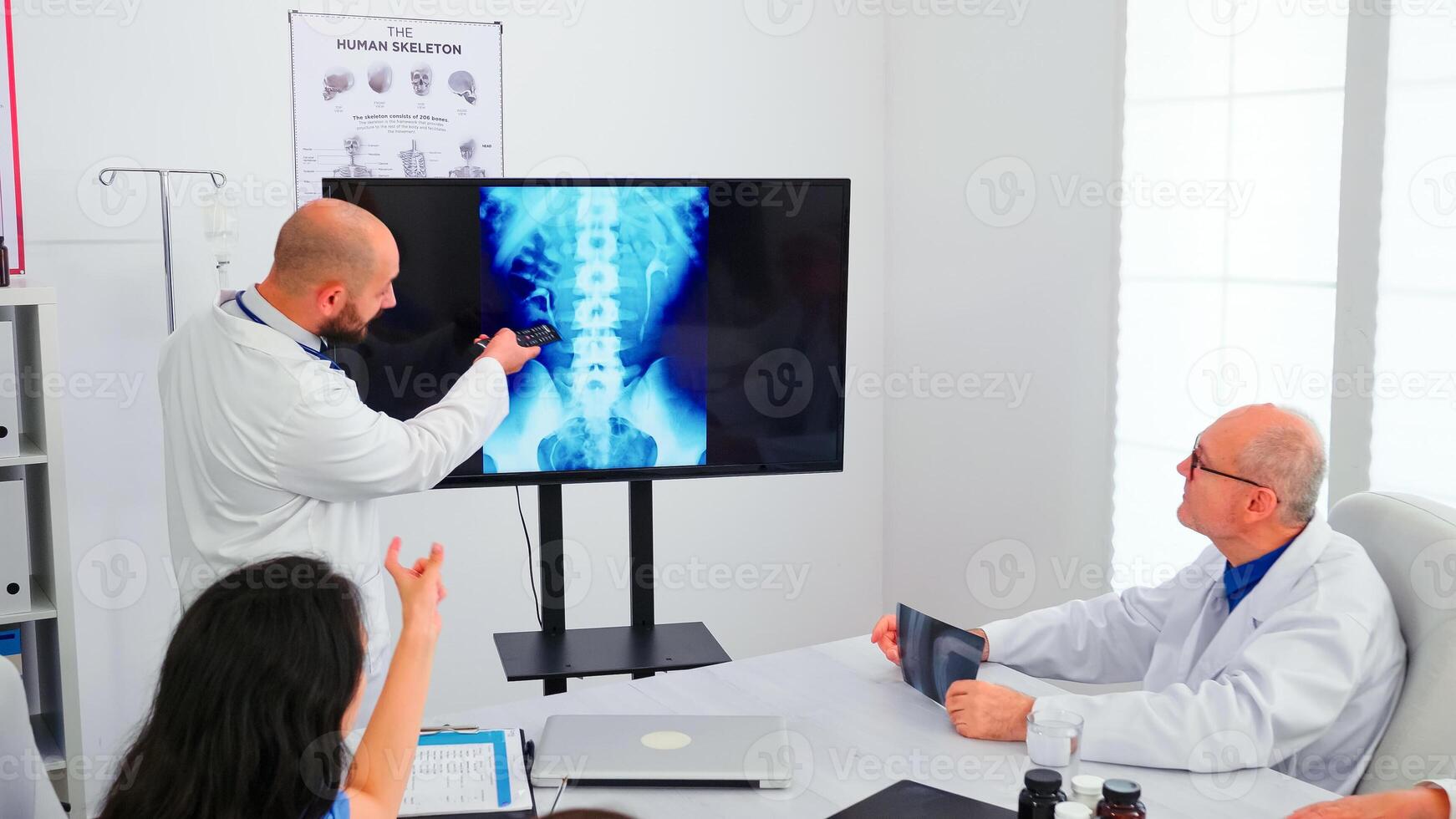 Expert doctor holding medical training using modern technology, presenting digital radiography to coworkers. Radiologist analysing x-ray spin image discussing symptoms of disease for further treatment photo