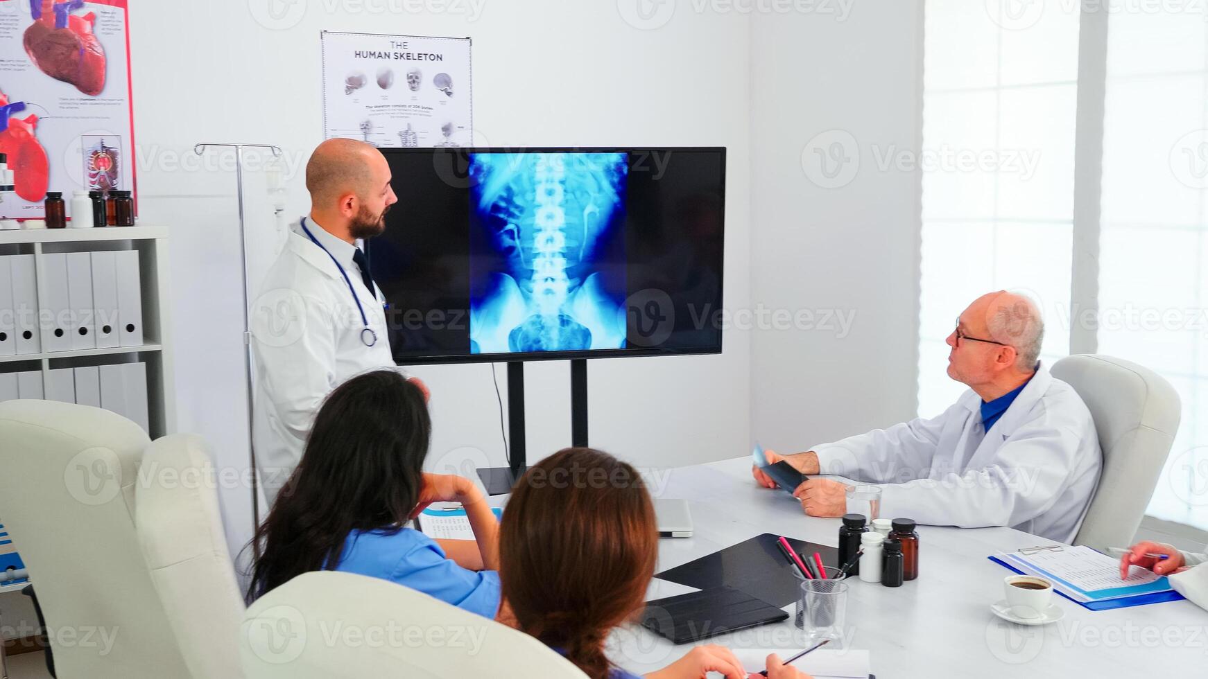 Group of doctors listening medical expert during medical conference analysing digital radiography, pointing on monitor. Physicians using modern technology discussing diagnosis about patients treatment photo