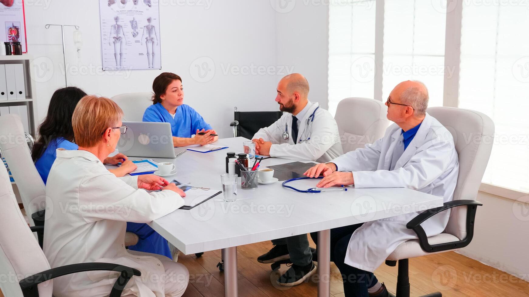 Team of expert doctors sitting at desk in hospital conference room having a briefing. Clinic expert therapist talking with colleagues about disease for treatment development, medicine professional photo