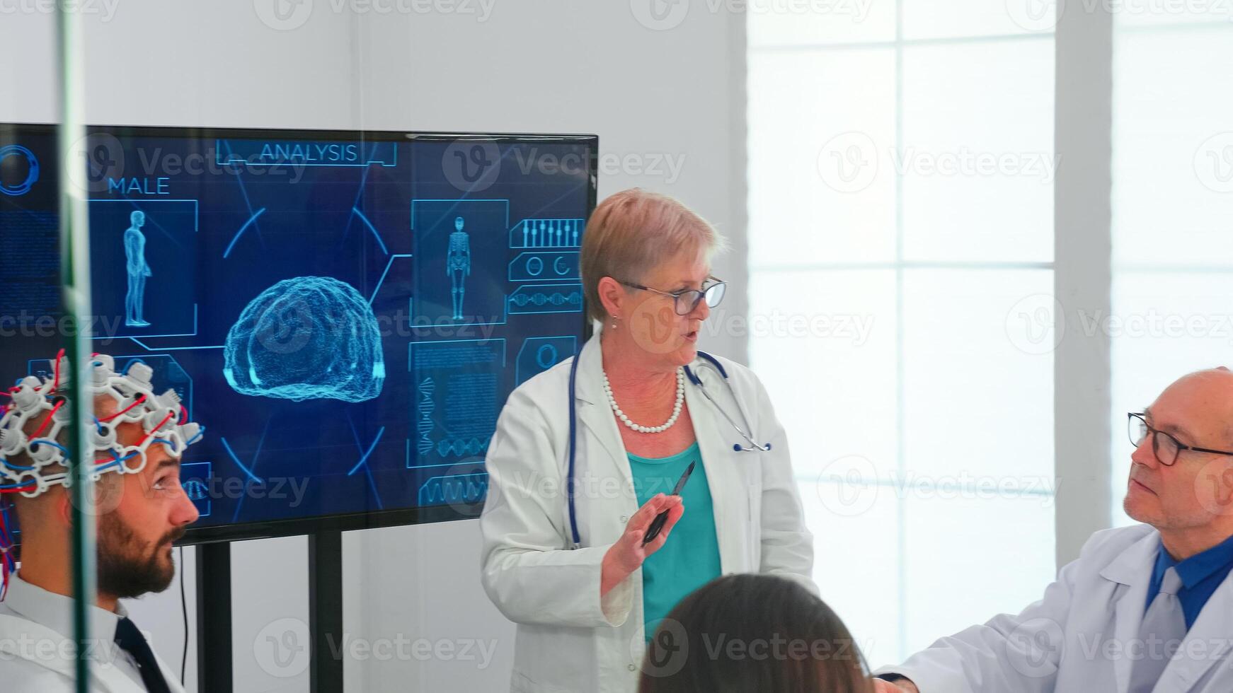 Brainwave electroencephalograph examination in hospital brainstorming office by medical physician. Monitor shows modern brain study while team of scientist adjusts the device. photo