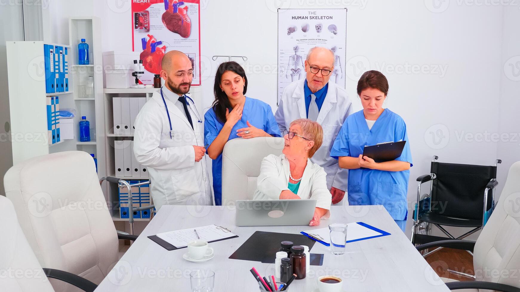 Team of doctors looking at laptop in conference room wearing medical uniform working in conference meeting room. Clinic expert therapist talking with colleagues about disease, medicine professional photo