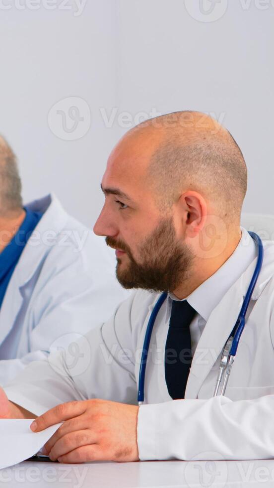 Brainstorming teamwork of physicians solving problems of patients in modern hospital meeting room having medical conference. Team of doctors talking about symptoms of disease in clinic office. photo