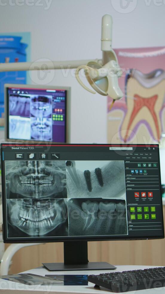 Interior of modern dentistry medical room with special stomatologial equipment. Stomatology clinic with nobody in prepared for next patient with radiograph displayed on computer screen photo