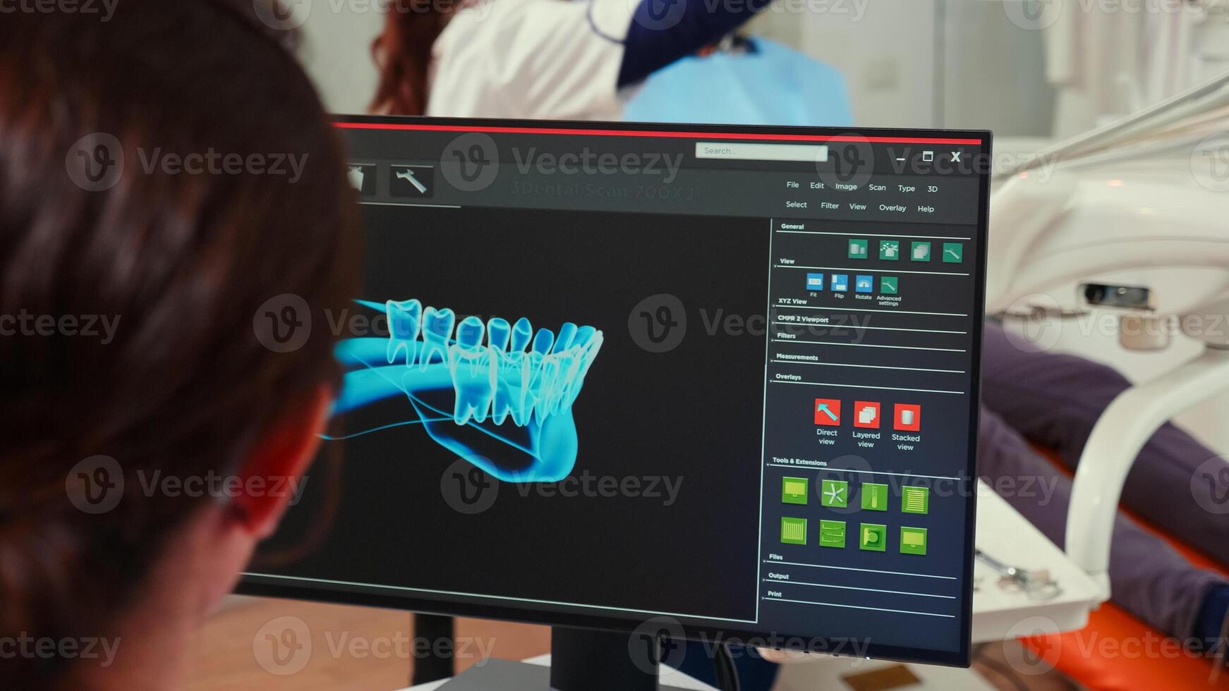 Stomatologist nurse looking at digital dental fingerprint on computer sitting in stomatological clinic while dentistry doctor is working with patient in background examining teeth problems. photo