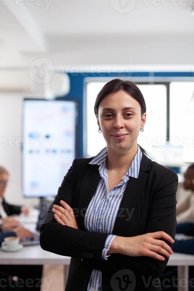 Woman entrepreneur smiling at camera standing in conference room, preparing for meeting with partners. Manager working in professional start up financial business, modern company workplace ready for meeting. photo