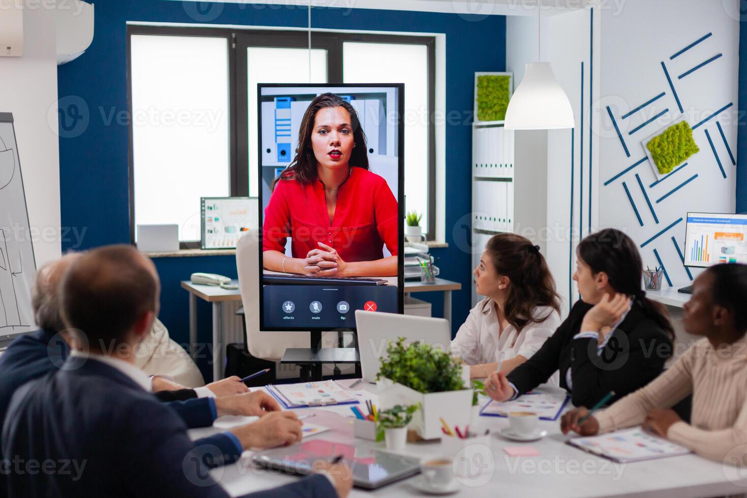 Diverse executive team meeting at conference call looking at huge display. Business people talking to webcam, do online conference participate internet brainstorming, distance office discussion photo