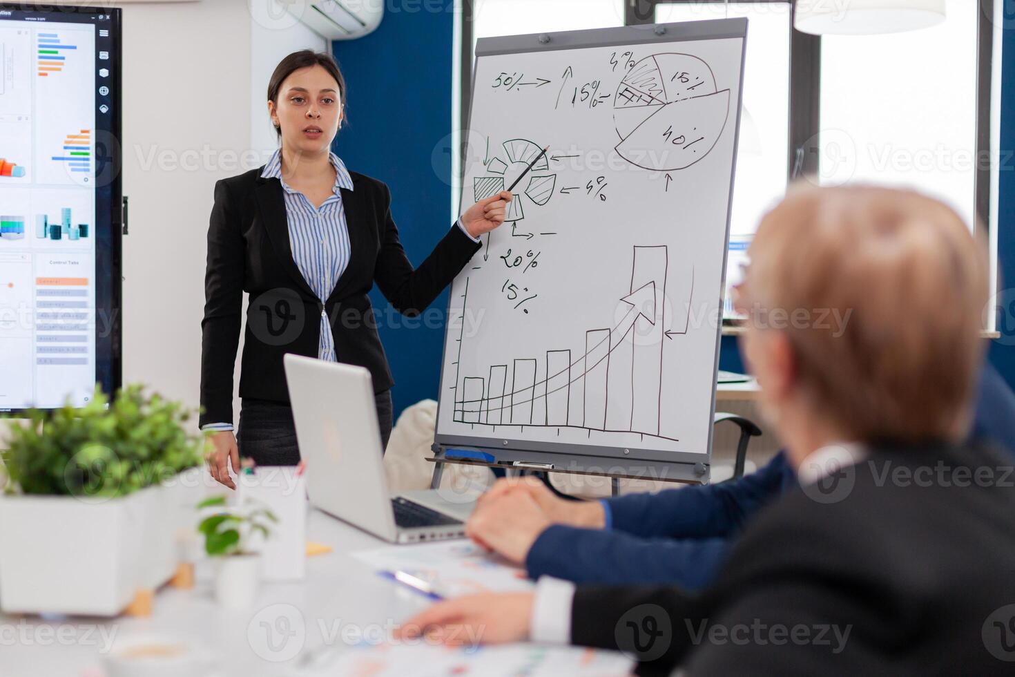 Leader making sales report for top company managers drawing charts on white board. Serious speaker boss executive, business trainer explaining development strategy to motivated mixed race employees. photo