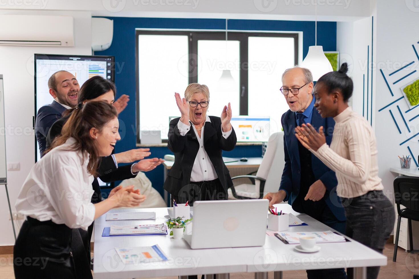 Diverse executive business team clapping in conference room during training. Multiethnical partners coworkers celebrate successful teamwork result at company briefing photo