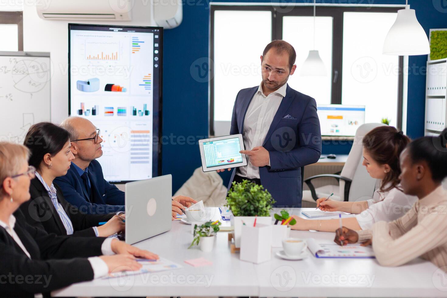 Company leadership explaining briefing project in conference room to team. Project leader discussing with teamworkers in broadroom, analysing charts, graphs, financial evolution of company. photo