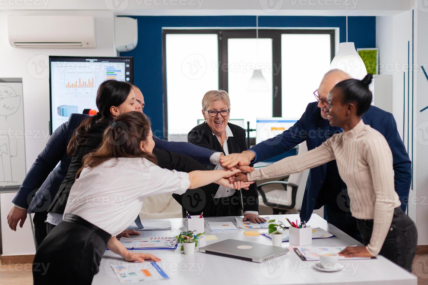 Happy creative multiethnic business team celebrating successful project. Diverse colleagues with new opportunity enjoing victory meeting in broadroom office. photo