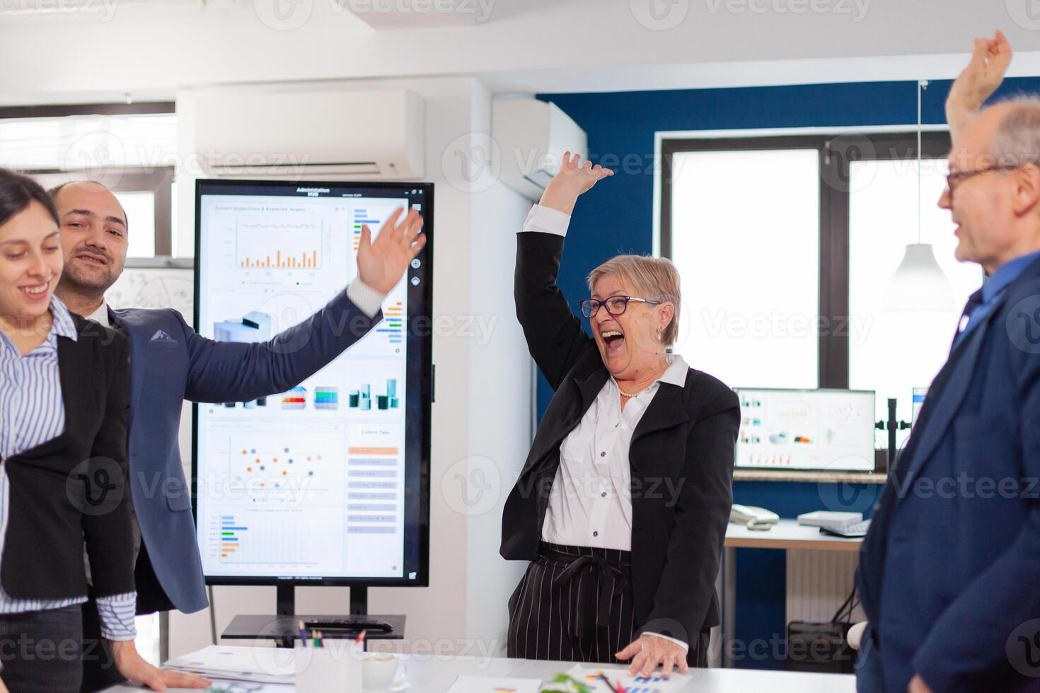 Happy victorious business people in start up company celebrating with hands rised in conference room. Diverse colleagues with new opportunity enjoing victory meeting in broadroom office. photo