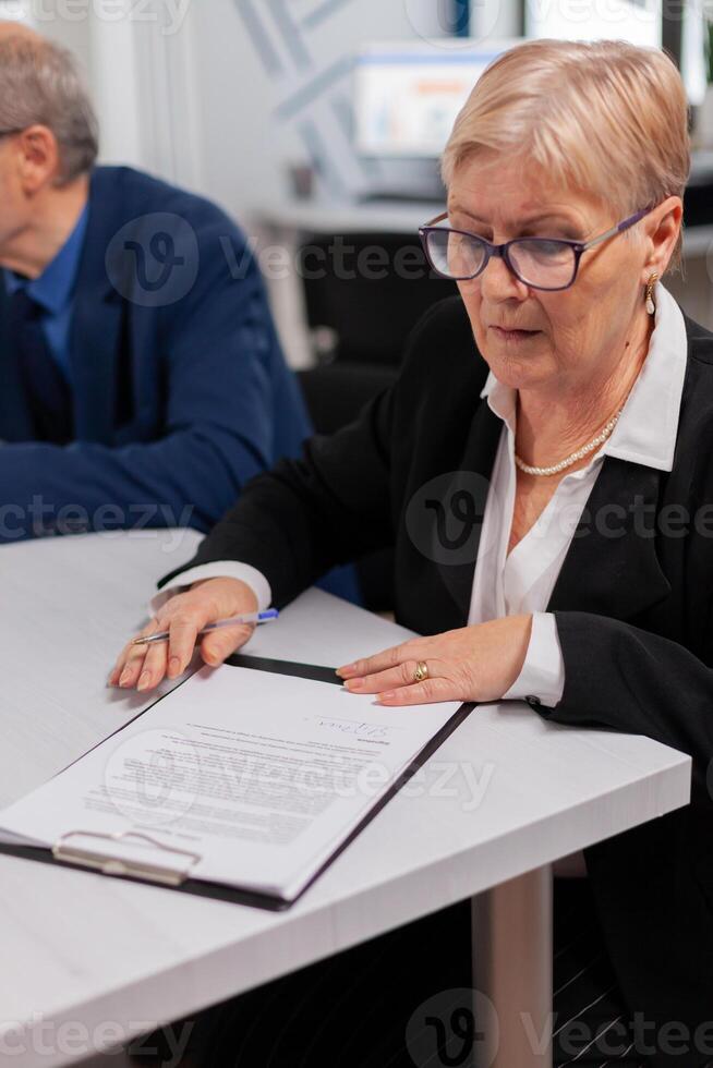 Woman reading financial documents in conference room before signing it. Executive director meeting shareholders in start up office, making satisfactorily agreement. photo